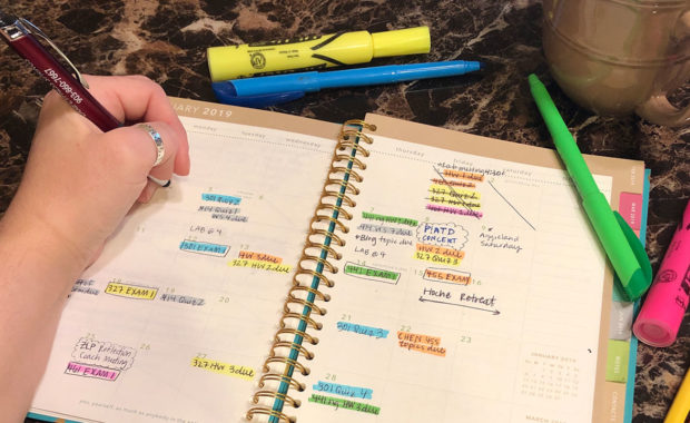 Monthly planner surrounded by highlighters and a cup of coffee.