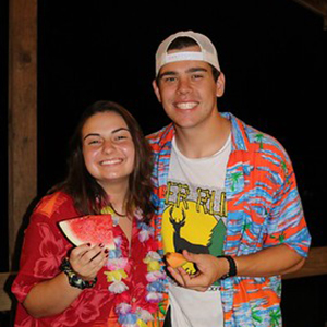 Danielle and a male counselor pose for a picture with watermelon slices in hand.