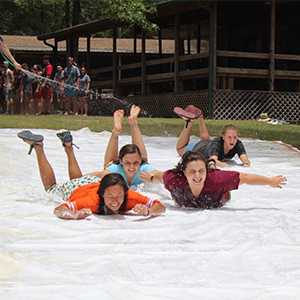 Danielle and campers slide belly first down a slip n slide.