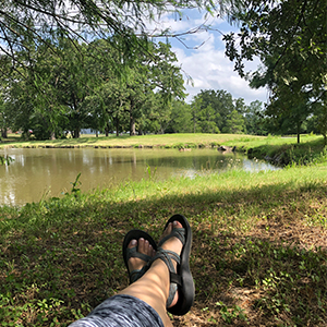 Danielle's perspective of sitting on the ground at Research Park overlooking the pond just beyond her feet.