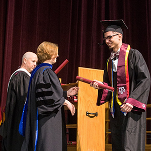 Luis Moreno accepts his degree from Dr. M. Katherine Banks on stage at graduation.