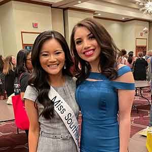 two women dressed formally for a scholarship pageant competition standing together and smiling