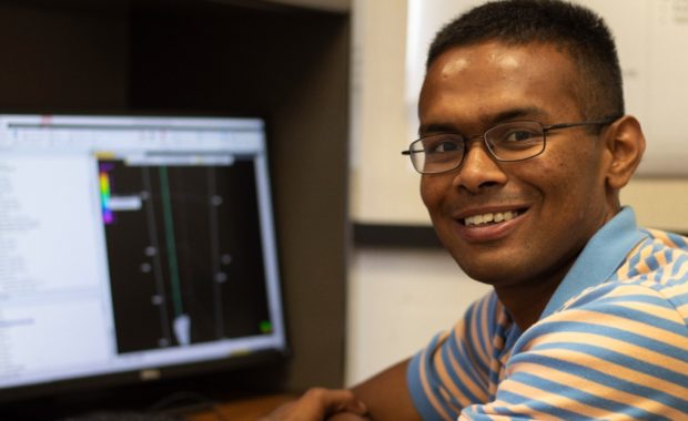 Texas A&M University student Prakhar Sarkar smiling while sitting in front of a computer
