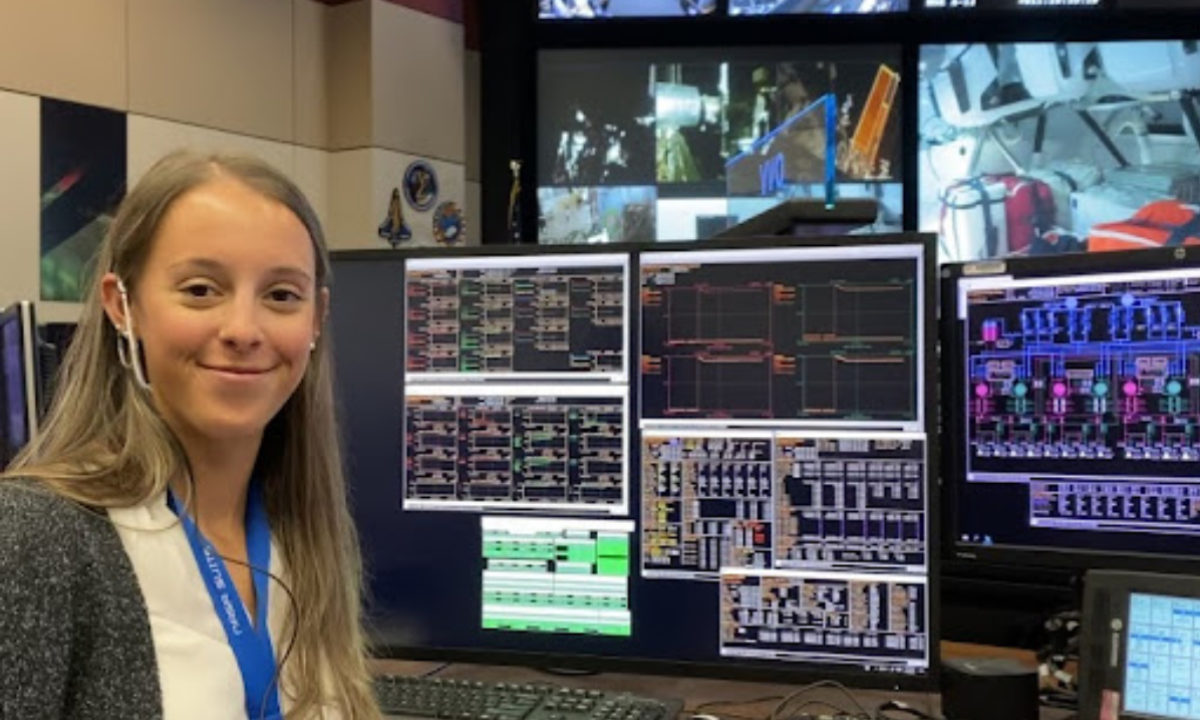 Student, Leah Davis, sitting in front of flight operations computers and tvs