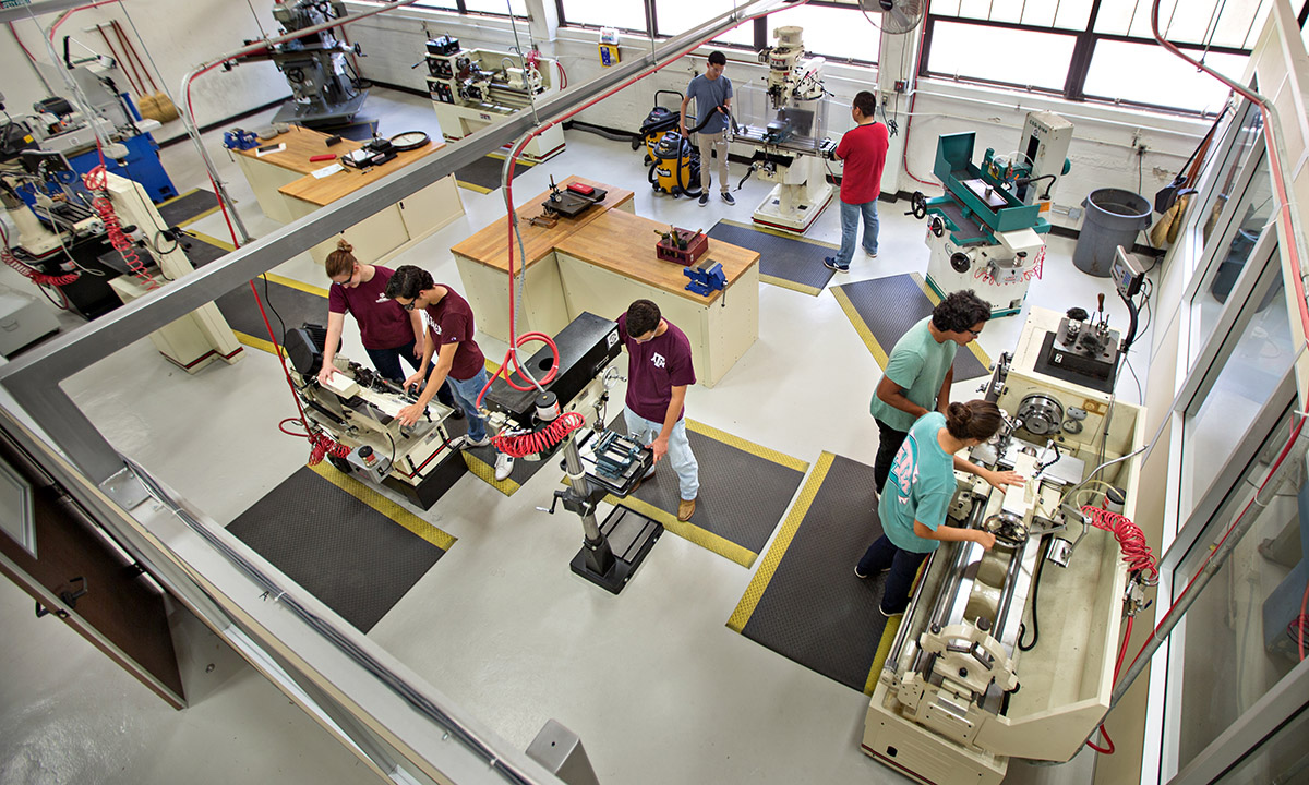 large industrial equipment lab featuring various machinery with students at the controls