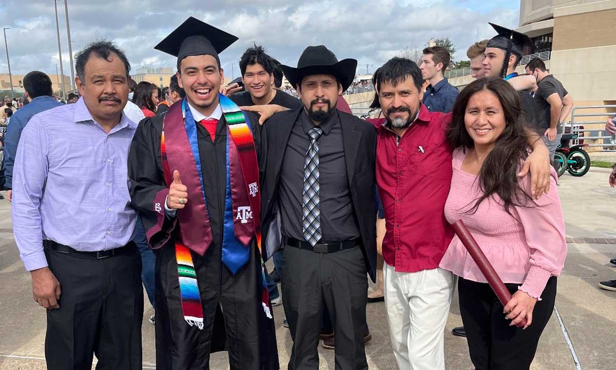 First generation Aggie graduate posing with happy family members