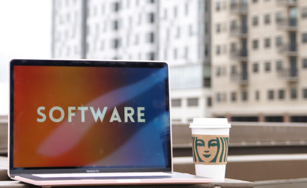 The word "Software" on a laptop with buildings in the background