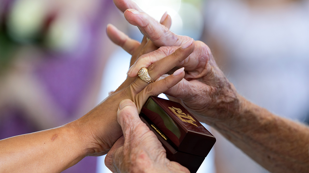 Hands putting an Aggie ring on another hand