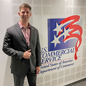 Austin Kees in front of the U.S. Commercial Service logo