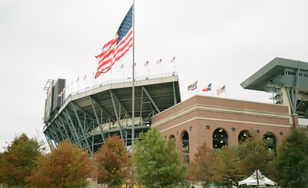 The American flag blowing in the breeze with Texas A&M's Kyle Field in the background.