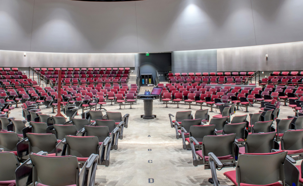 An empty classroom with the speaker podium in the center of chairs arranged in a circle.